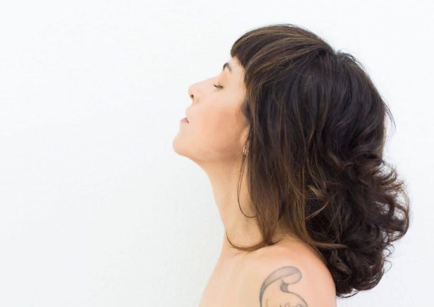 Mariana de perfil, com cabelo médio escuro em camadas